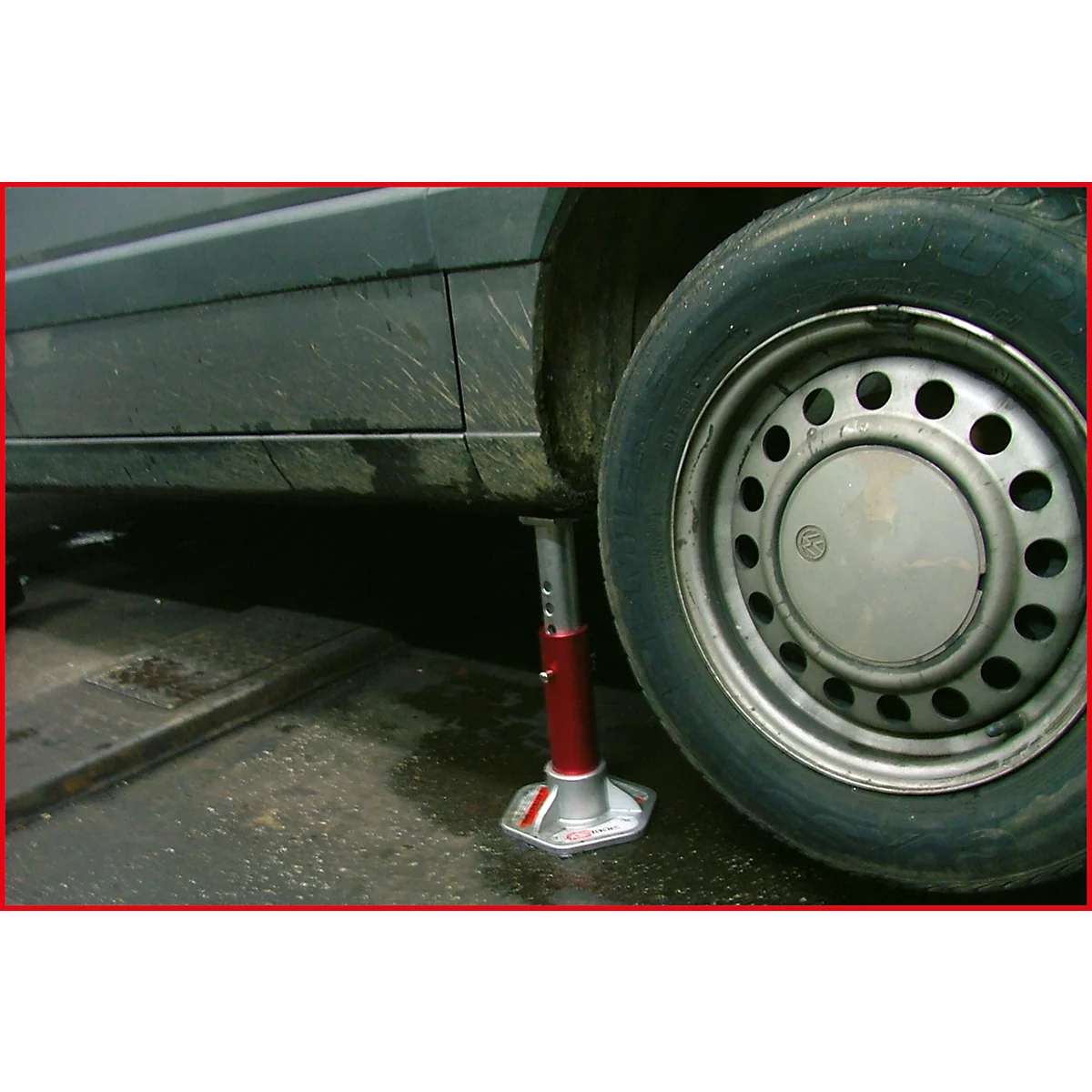 Ein Auto wird mit einem roten Wagenheber angehoben, um einen Reifen zu wechseln.